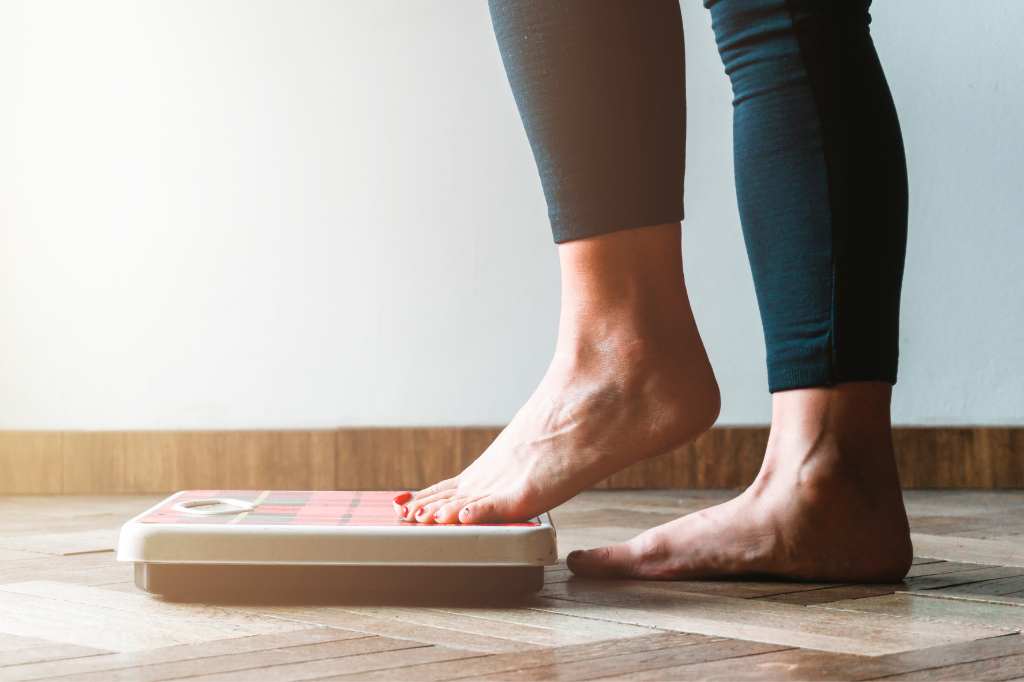 woman stepping on weight loss scale